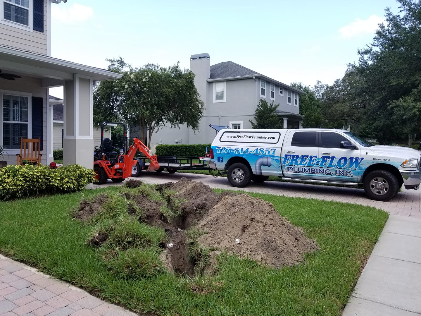 Free-Flow Plumbing truck and excavator at sewer line replacement job in New Port Richey, FL